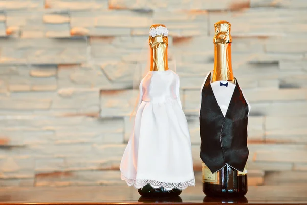 Dwie butelki szampana w stroje panny młodej i pana młodego w tabeli. miejsce — Zdjęcie stockowe