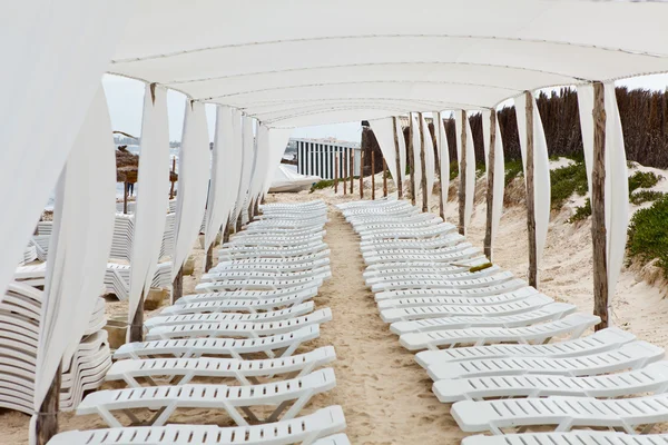 Bílá plastová lehátka v písečné pláži pod velkým slunečníkem — Stock fotografie
