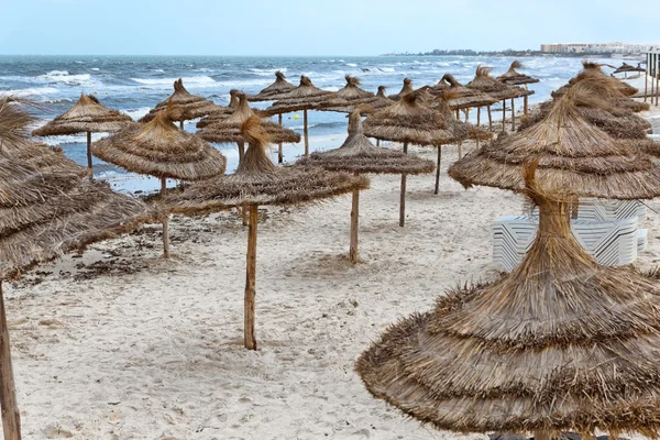 Costa mediterránea de mar tormentoso y playa de arena vacía con sombrillas Costa mediterránea de mar tormentoso y playa de arena vacía con sombrillas —  Fotos de Stock