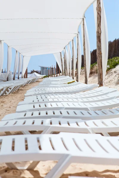 白色塑料日光浴浴床的大阳伞下的沙滩 — 图库照片