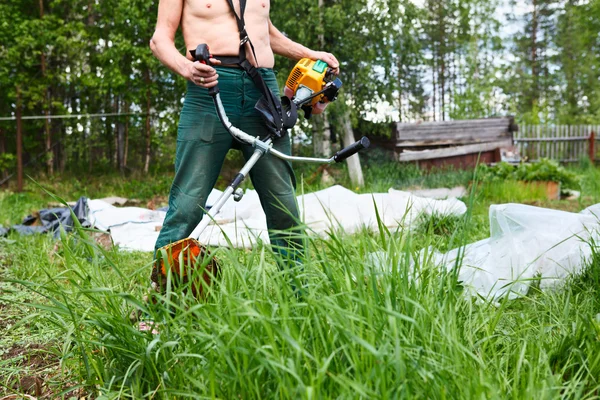 Unerkennbarer Rasenmäher mit Hackentrimmer beim Rasenmähen. Trimmer im Fokus — Stockfoto