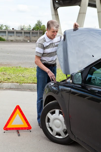 Maduro homem com aberto carro capuz e emergência triângulo sinal no estrada — Fotografia de Stock