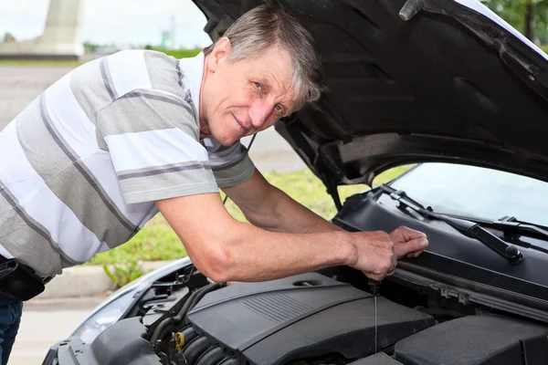 Ώριμος καυκάσιος άνδρας τον έλεγχο ένα επίπεδο πετρελαίου κάτω από αυτοκίνητο κινητήρα σακάκι — Φωτογραφία Αρχείου