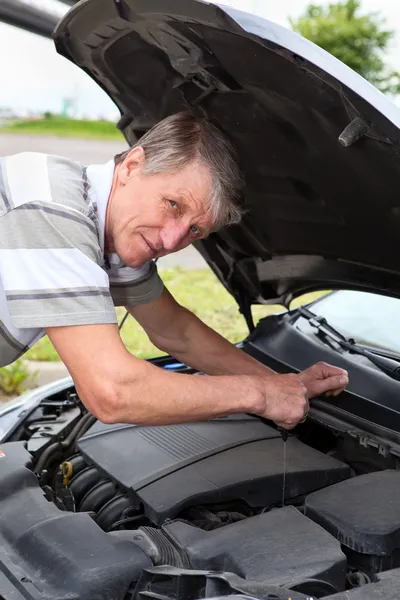 Volwassen Kaukasische man controle op een olie onder auto motorkap — Stockfoto