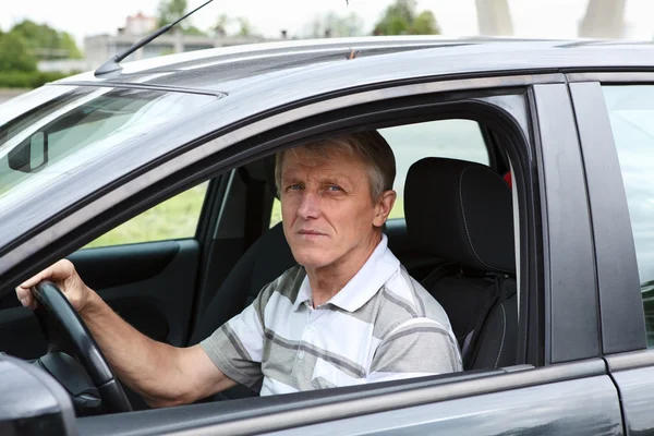 Зрелый мужчина, сидящий в машине на водительском сидении и держащий руль — стоковое фото