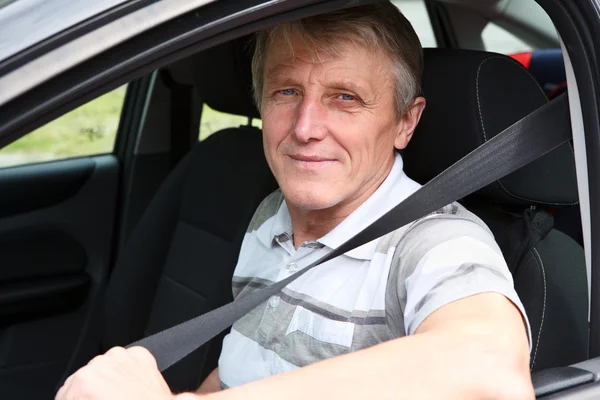 Красивый взрослый мужчина пристегивает ремень безопасности, сидя в машине на водительском сидении — стоковое фото