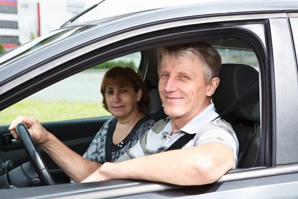 Зрелая счастливая белая пара, сидящая в машине и улыбающаяся — стоковое фото