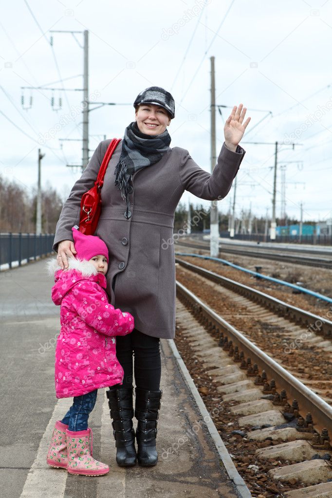 Mother and small daughter standing on railway station platform