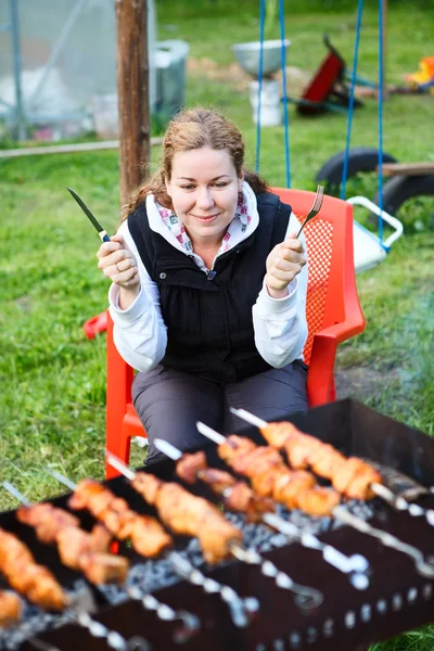 Mulher com garfo e faca nas mãos sentado e esperando por carne grelhada — Fotografia de Stock