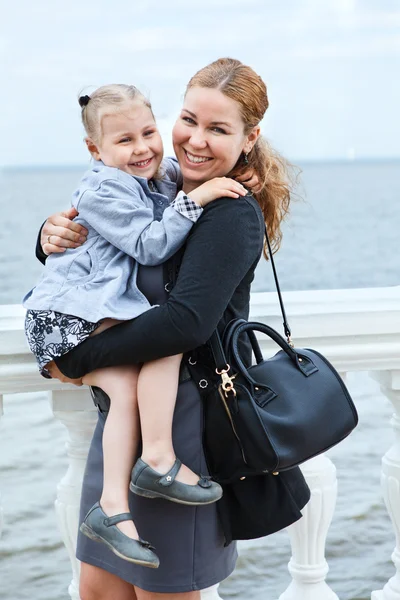 Happy mother and little daughter together Small child on womans hands. Caucasian standing on sea coast — Stock Photo, Image