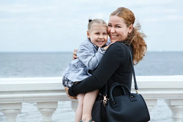 Щасливі матері і маленька дочка разом маленької дитини на руках жінки. Кавказька, стоячи на узбережжі моря — стокове фото