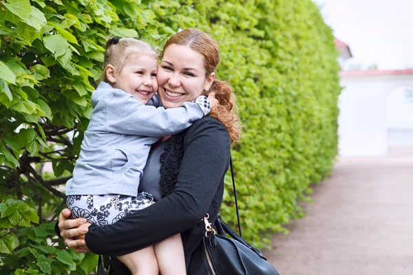 Szczęśliwą matką i małe razem córka dziecko na ręce womans. miejsce. zielony liść jako tło — Zdjęcie stockowe