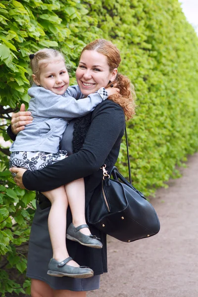 Щаслива мати і маленька донька разом маленька дитина на руках жінок. Копіювати простір. Зелений лист як фон — стокове фото
