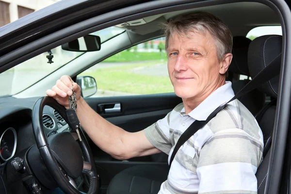 Счастливый водитель с ключом от машины, сидящий в своей машине — стоковое фото