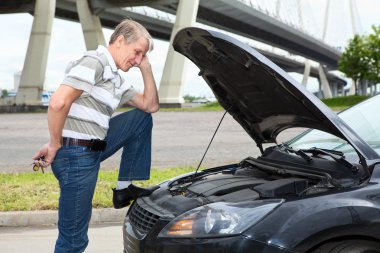 Confused mature driver standing front of car with opened engine compartment hood clipart