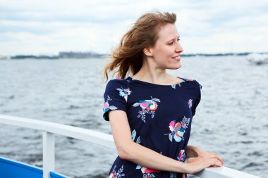 Girl standing on the deck of cruise yacht on wind and looking far away clipart