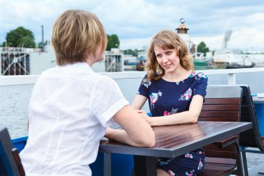 Two frendly talking girlfriends at cafe table clipart