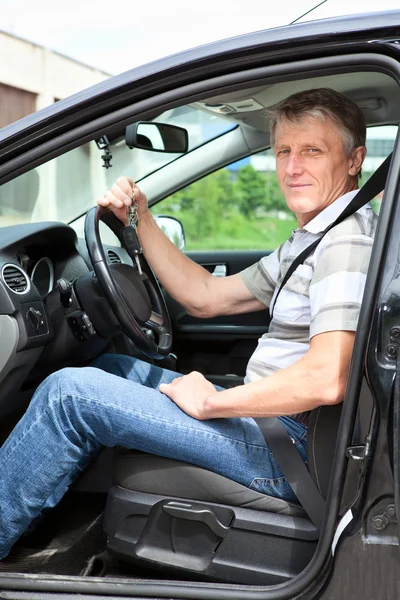 Щасливий старший водій з ключем від машини в машині — стокове фото