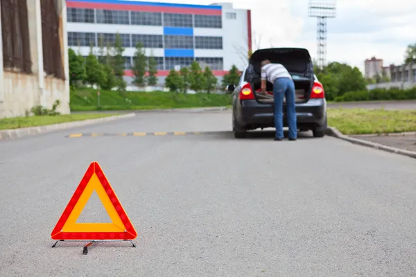 कार सामान रॅकमध्ये रस्त्यावर त्रिकोण चेतावणी चिन्ह आणि ड्रायव्हर — स्टॉक फोटो, इमेज