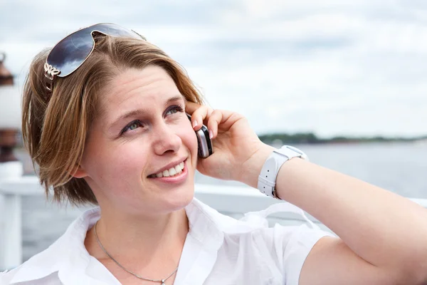 Ελκυστική γυναίκα σε άσπρο πουκάμισο με γυαλιά ηλίου καλεί από κινητό τηλέφωνο. κοντινό πλάνο — Φωτογραφία Αρχείου