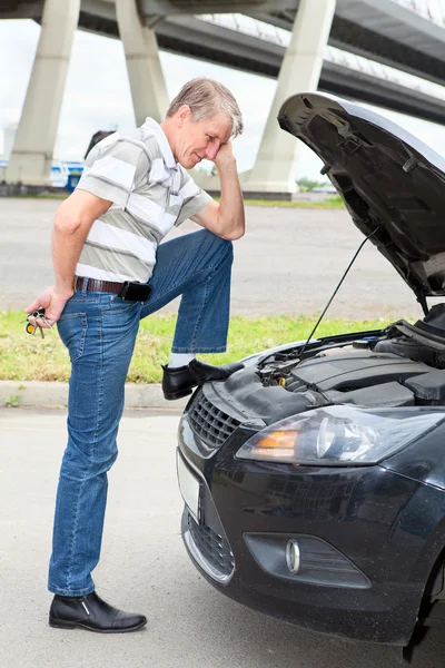 Confused driver standing front of car with opened engine compartment hood — Stock Photo, Image