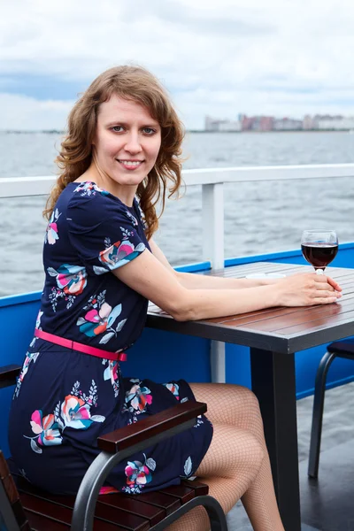 Uscita donna bianca in abito con bicchiere di vino rosso a tavola — Foto Stock