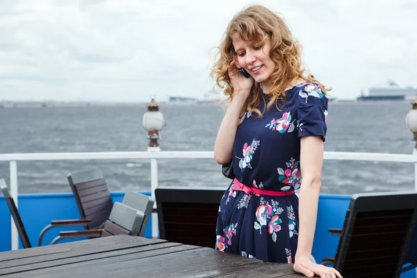 Happy standing woman on ship deck cafe with mobile telephone — Stock Photo, Image