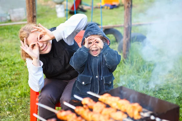 Mère et petite fille faisant des visages pendant la cuisson de la viande — Photo