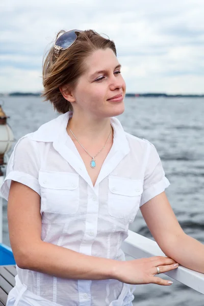 Vrouw in wit overhemd met zonnebril permanent op het dek van het schip in de buurt van rails — Stockfoto