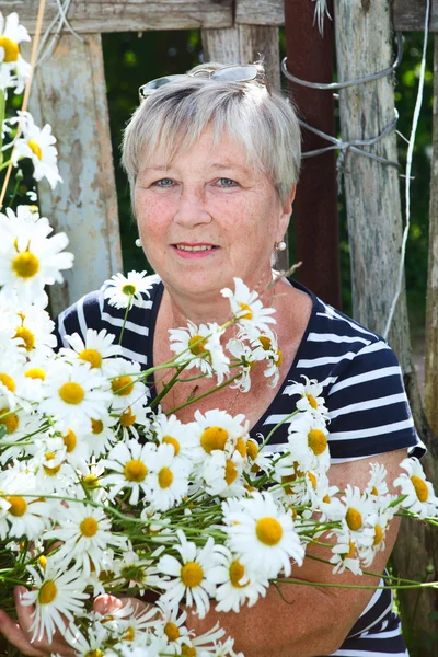 Senior adult female holding growing chamomiles — Stock Photo, Image