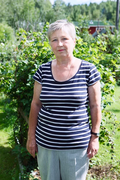 Senior Caucasian woman standing in green garden — Stock Photo, Image