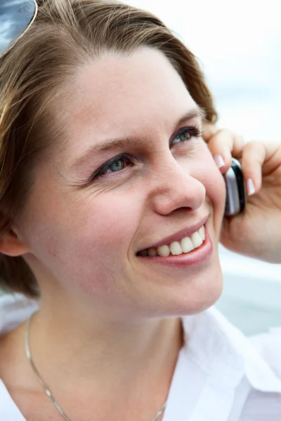Donna felice in camicia bianca con occhiali da sole che chiama sul cellulare. Da vicino. — Foto Stock