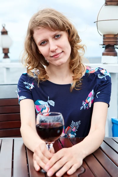 Γαλήνια ομορφιά γυναίκα στην φόρεμα με ποτήρι κρασί που κάθεται στο τραπέζι — Φωτογραφία Αρχείου