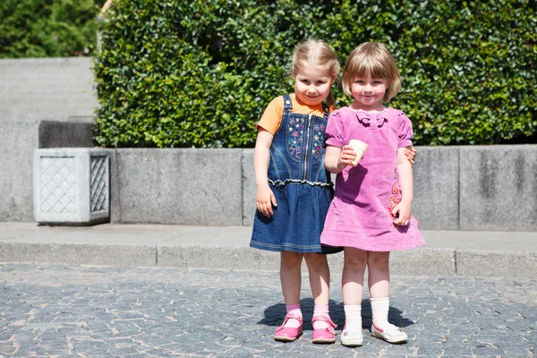 Two sweet little girls standing together with one ice cream. Copyspace — Stock Photo, Image