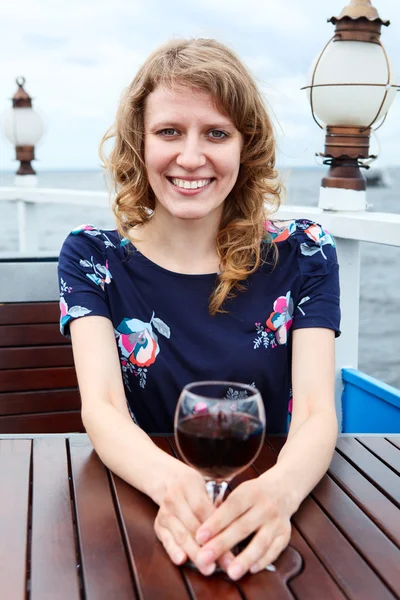 Γυναίκα ευτυχισμένη ομορφιά στο φόρεμα με ποτήρι κρασί που κάθεται στο τραπέζι — Φωτογραφία Αρχείου