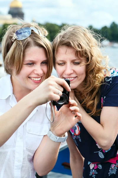Zwei schöne Frauen, die auf den Bildschirm einer einfachen Handkamera blicken — Stockfoto