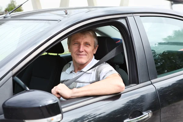 Vastgemaakt lachende Kaukasische senior man zit in auto op bestuurdersstoel — Stockfoto