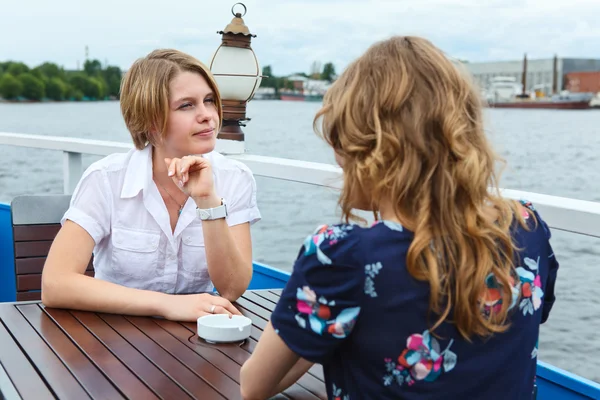 Молодая женщина сидит напротив подруги за столиком кафе — стоковое фото