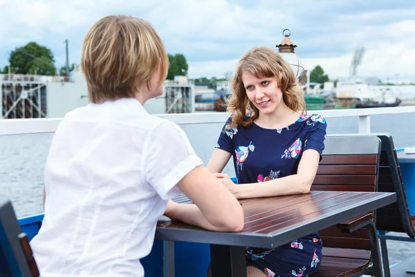 stock image Two frendly talking girlfriends at cafe table