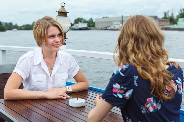Twee gelukkige vriendinnen praten elkaar op café tabel buitenshuis — Stockfoto