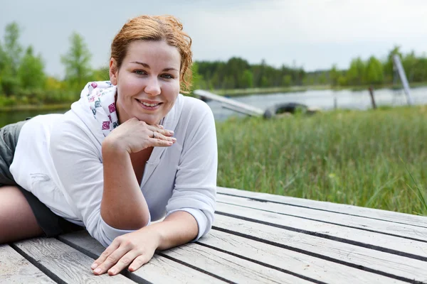 Happy smiling woman laying on wooden boards on river edge. Copyspace — Stock Photo, Image