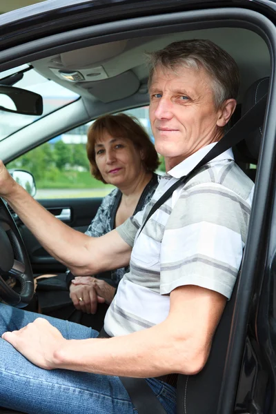 Mature male and woman sitting in land vehicle and smiling — Stock Photo, Image