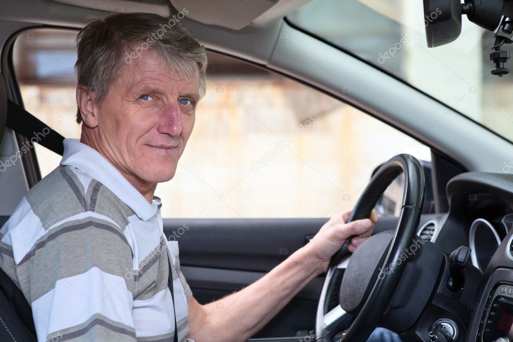 Experienced driver mature Caucasian male holds steering wheel in own car