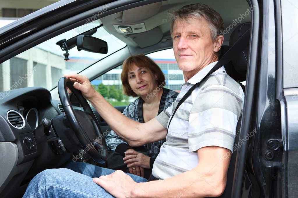 Senior Caucasian husband and wife sitting in land vehicle and smiling