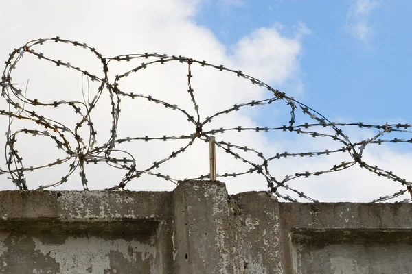 stock image Stone wall with barbed wire against blue sky