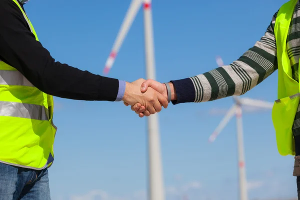 Engenheiros dando aperto de mão em uma usina eólica turbina — Fotografia de Stock
