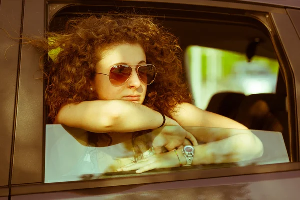 Застенчивая девушка, выглядывающая из окна автомобиля — стоковое фото