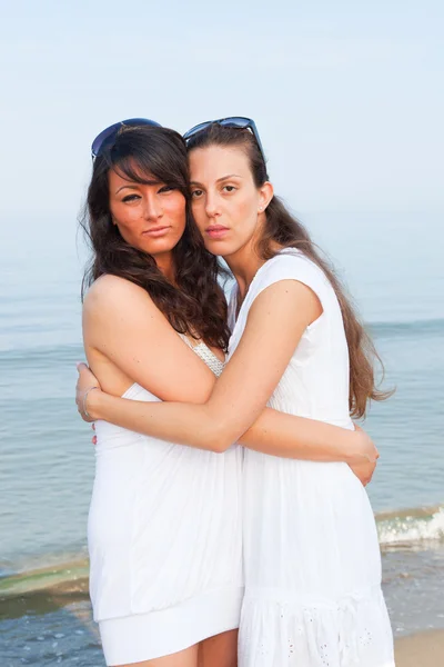 Due amiche abbracciate sulla spiaggia — Foto Stock