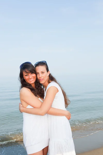 Twee vrouwelijke vrienden omarmd op het strand — Stockfoto