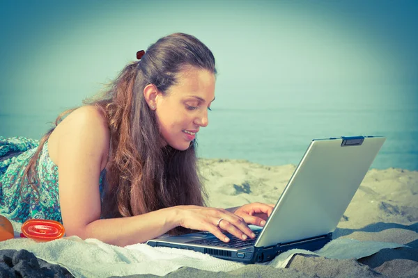 Женщина за компьютером на пляже — стоковое фото